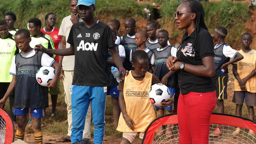 The founder of Aliguma Foundation Ritah Aliguma handing over the sports kits to the young football players in Acholi quarters Slums which were donated to them by the Uefa president Aleksander Ceferin last Friday