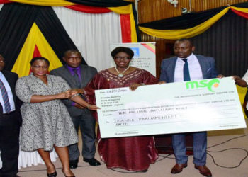 Speaker Kadaga (C) hands over a dummy cheque to the UPPA. On her left is Hon Kasolo Kyeyune with Hon Bahati(L) looks on