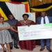 Speaker Kadaga (C) hands over a dummy cheque to the UPPA. On her left is Hon Kasolo Kyeyune with Hon Bahati(L) looks on