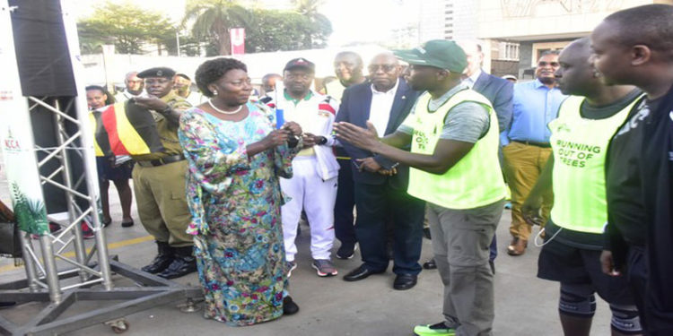 Kadaga (L) hands over a baton to one of the runners