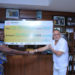 Dr Sudhir handing over a cheque to Ruth Nankabirwa