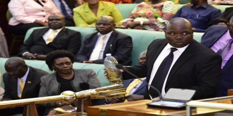 MP Abala holding a bottle containing locusts while in the House