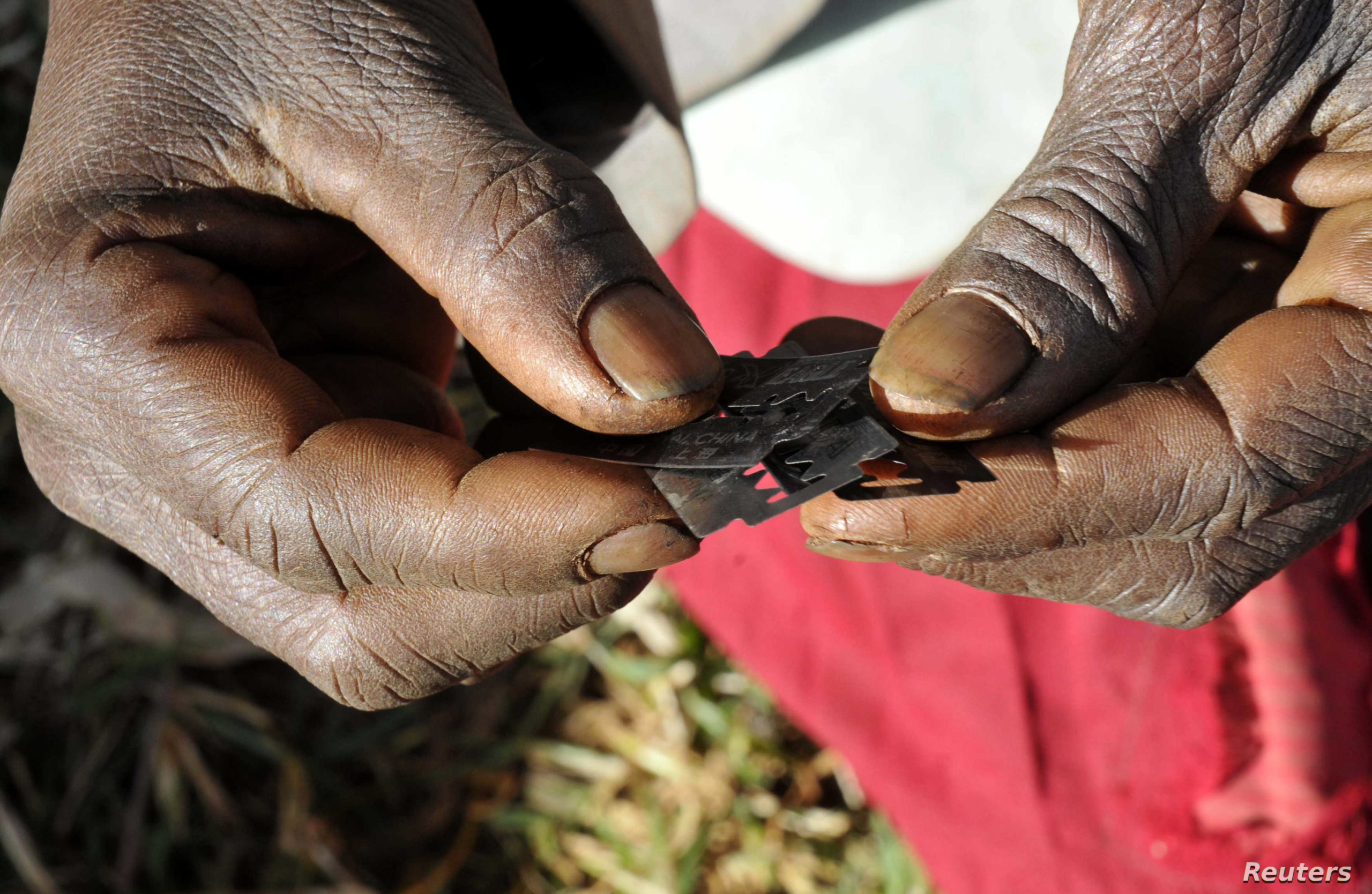 Prisca Korein, a 62-year-old traditional surgeon, holds razor blades before carrying out female genital mutilation on teenage girls from the Sebei tribe in Bukwa district, about 357 kms (214 miles) northeast of Kampala, December 15, 2008. The ceremony was to initiate the teenagers into womanhood according to Sebei traditional rites. REUTERS/James Akena (UGANDA) - RTR22M64