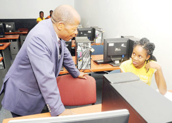 Minister-Chrysostom-Muyingo-engages-a-student-in-a-computer-lab.