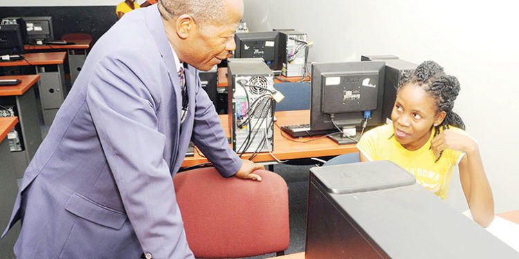 Minister-Chrysostom-Muyingo-engages-a-student-in-a-computer-lab.