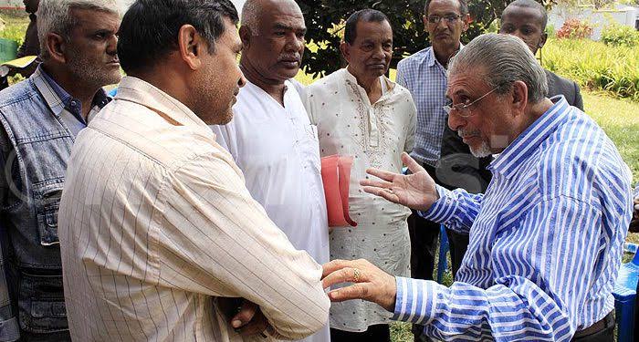 Tycoon Mohammed Alibhai [blue shirt]is accused of grabbing properties belonging to Asians