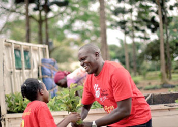 Environmentalist Joseph Masembe handing over a tree seedling to a kid