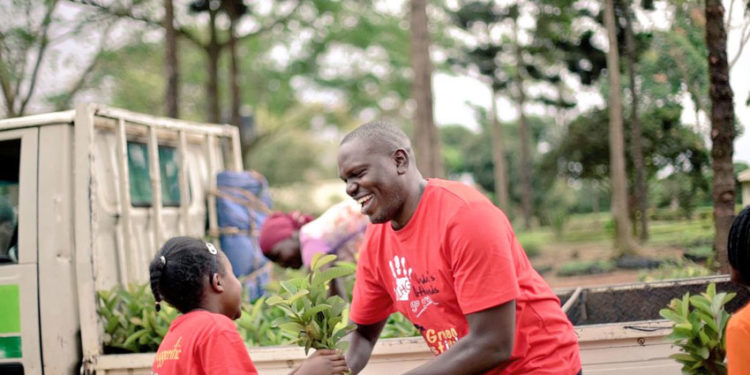 Environmentalist Joseph Masembe handing over a tree seedling to a kid