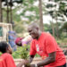Environmentalist Joseph Masembe handing over a tree seedling to a kid
