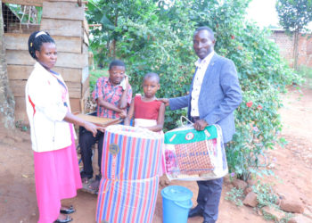 Dorothy Nakiryowa receiving donated items; Bed sheet and a blanket from Gideon Kabenge who is currently taking care of his brother Ssebaduka.