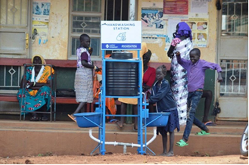 A street child washes her hands using a hand operated hand washing station