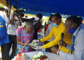 Minister Tumwebaze handing over Shs150,000 to a SAGE beneficiary in Lira town
