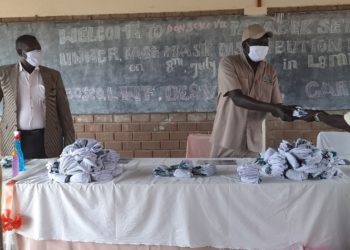 Mr. Robert Ocan, the Refugee Chairman receiving masks on behalf of refugees