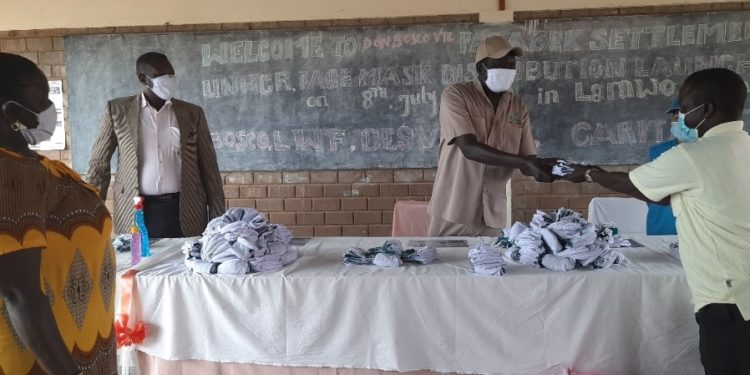 Mr. Robert Ocan, the Refugee Chairman receiving masks on behalf of refugees