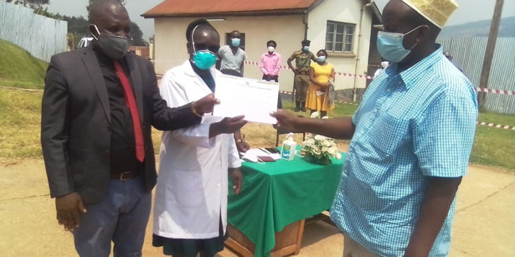  Bashir is receiving his covid-19 certificate from Darius Nandinda and the hospital director.