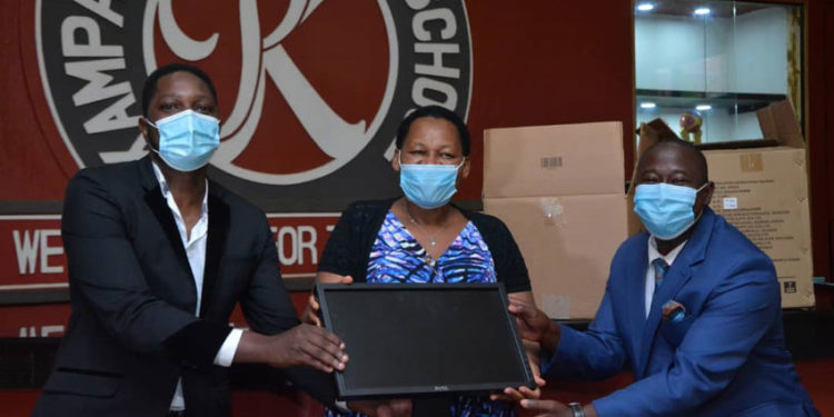 Mr Onyango Gareth, Mrs Daphine Kato handing over computers to Mr Solomon Serwanja