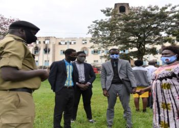 The LOP, Hon. Betty Aol Ocan (R), receiving a brief from a Police officer at Makerere University. In the background is the Main Building