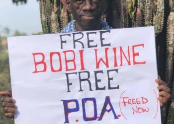 Dr Besigye with a #FreeBobiWine placard