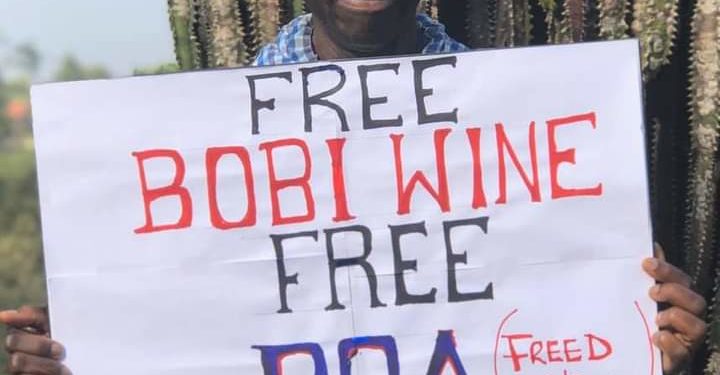 Dr Besigye with a #FreeBobiWine placard