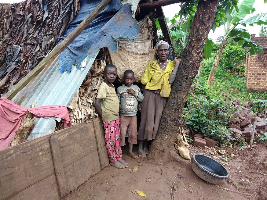 One of the beneficiaries  Josephine Nabwegamu with her grandchildren standing next to their substandard shelter