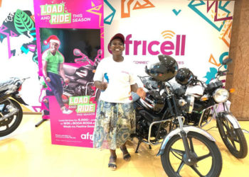 Ms Jackqueline Sebunya, a water vendor and resident of Wabigalo in Kibuli, a Kampala suburb poses for a photo after winning a brand new Boda Boda in the ongoing Africell load and ride promotion
