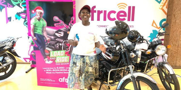 Ms Jackqueline Sebunya, a water vendor and resident of Wabigalo in Kibuli, a Kampala suburb poses for a photo after winning a brand new Boda Boda in the ongoing Africell load and ride promotion