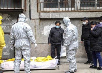 Funeral home workers remove the body of a person suspected to have died from the coronavirus outbreak from a residential building in Wuhan, Hubei Province, on February 1, 2020.   –   Copyright  Chinatopix via AP, File