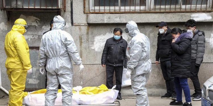 Funeral home workers remove the body of a person suspected to have died from the coronavirus outbreak from a residential building in Wuhan, Hubei Province, on February 1, 2020.   –   Copyright  Chinatopix via AP, File
