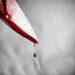 close-up of man holding knife smeared with blood and still dripping.