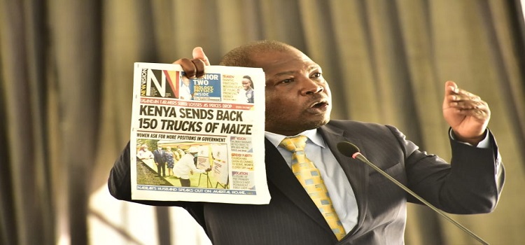 Hon Macho holds up a newspaper that run the story on the maize ban
