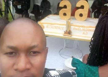 Kenneth Nsibambi and behind him is Kabaka's 66th birthday cake