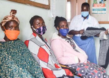 Anicia Filda in blue and white counsels women waiting for sterilisation at Atiak Health Centre IV