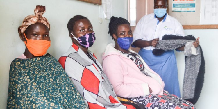 Anicia Filda in blue and white counsels women waiting for sterilisation at Atiak Health Centre IV