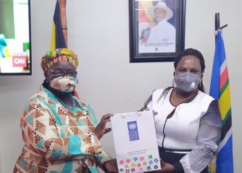 Minister Amongi (right) receives a gift pack from Elsie after the meeting