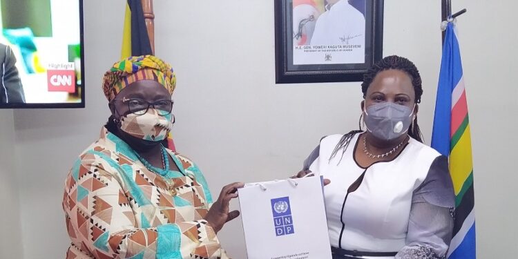 Minister Amongi (right) receives a gift pack from Elsie after the meeting
