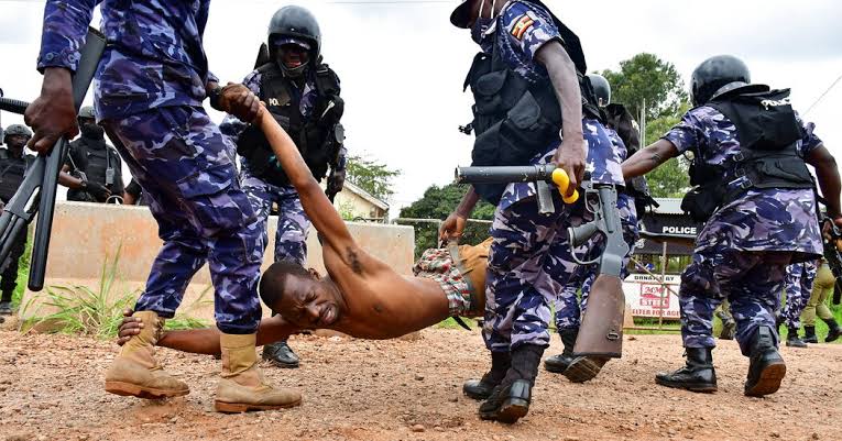 Police officers manhandling a Ugandan