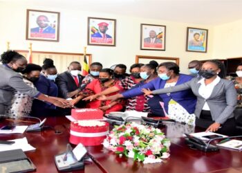 The LOP, Mathias Mpuuga (in red tie) cutting cake with colleagues to celebrate 100 days in office