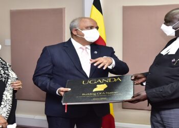 Oulanyah(R) hands a book about Uganda to Mehta. On the left is Mrs Mehta