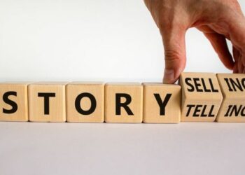 Storytelling or storyselling symbol. Businessman turns wooden cubes and changes the word 'storytelling' to 'storyselling'. Beautiful white background, copy space. Business and storytelling concept.