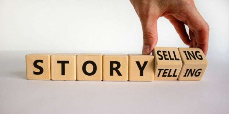 Storytelling or storyselling symbol. Businessman turns wooden cubes and changes the word 'storytelling' to 'storyselling'. Beautiful white background, copy space. Business and storytelling concept.