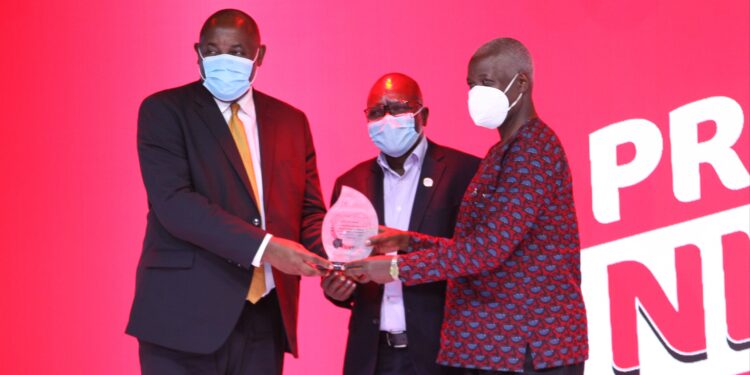 Mr John Kakande (right) receives his award from Minister Chris Baryomunsi