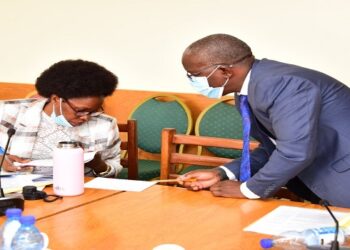 Minister Nabakooba (L) consults an official from her ministry during the meeting on the bill