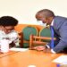 Minister Nabakooba (L) consults an official from her ministry during the meeting on the bill