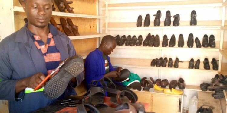 Simon Musisi Wesonga nga agatta engatto mu kkampuni ye eya WESOM SHOES LTD