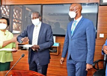 Finance minister Matia Kasaija (2nd left) exchanges documents with Enrica Pinetti (left) after signing an agreement with the Finance ministry to establish a coffee processing plant in Uganda