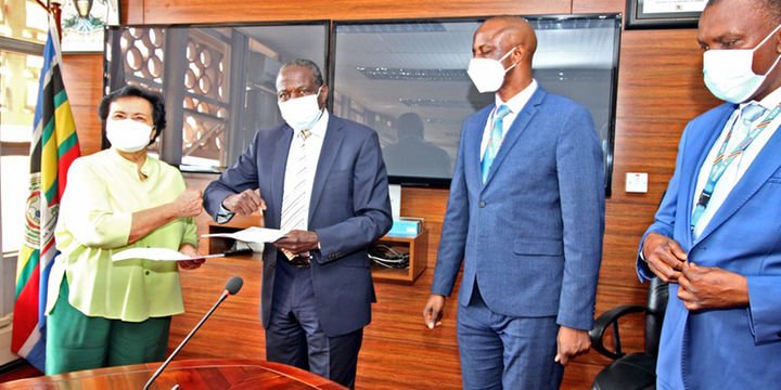 Finance minister Matia Kasaija (2nd left) exchanges documents with Enrica Pinetti (left) after signing an agreement with the Finance ministry to establish a coffee processing plant in Uganda