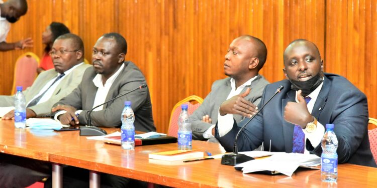 Lawyer Richard Buzibira (R) responding to questions from the committee as his partner, Kyle Lubega (2nd, R) gets lost in thought