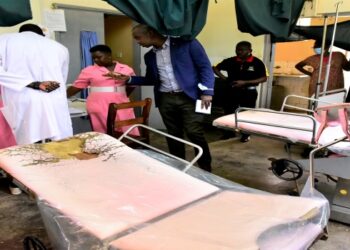 Committee chairperson, Dr Charles Ayume, being shown the books at Nagongera Health Centre IV in Tororo district