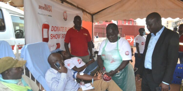 The Chief Guest Deputy Resident City Commissioner Jinja Mr Mike Ssegawa (Right) talking to the Uganda Blood Bank and Red Cross team during the donation of the blood drive by Nile Breweries Limited
