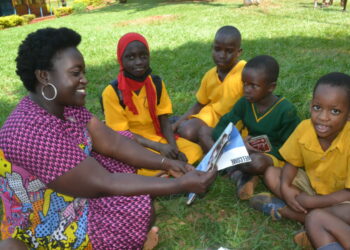 One of the Rotarians with pupils in group reading through the story books they donated to the pupils of Spire Road Primary School .PHOTO BY ANDREW ALIBAKU